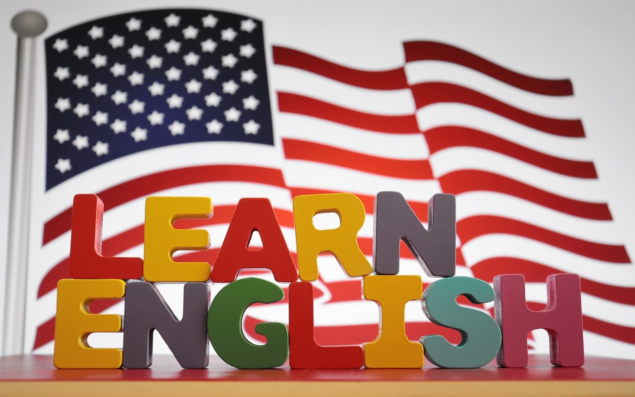 na rysunku w tle widać flagę USA a z przodu napis LEARn ENGLISH. rysunek z pixabay.com